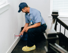 Mr. Electric electrician kneeling to install an electrical outlet cover.