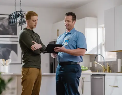 Home electrical repair service professional consulting with homeowner in kitchen