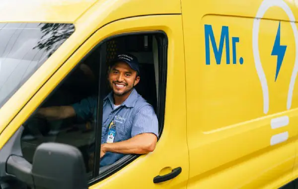 Smiling Mr. Electric electrician in truck.