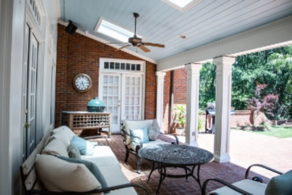 Outdoor patio area of a residential home with furniture, ceiling fan, and white French doors.