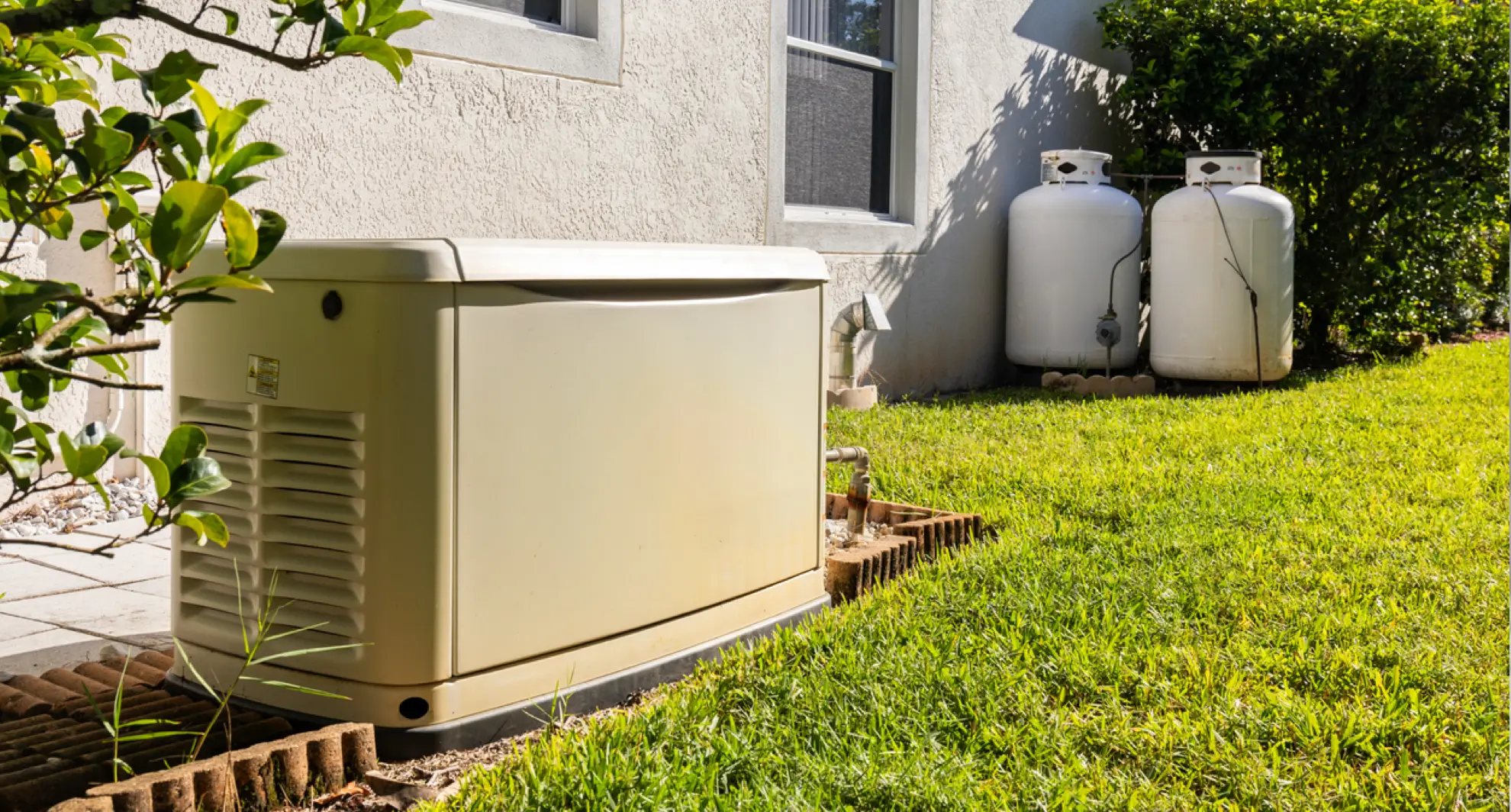 Standby home generator with propane tanks outside house