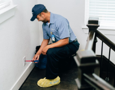 Electrician kneeling to install an electrical outlet cover.
