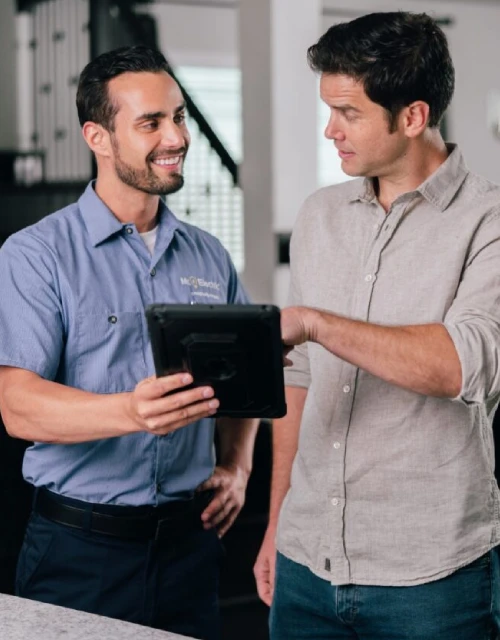 Mr. Electric tech speaking with a male customer in a tan shirt.