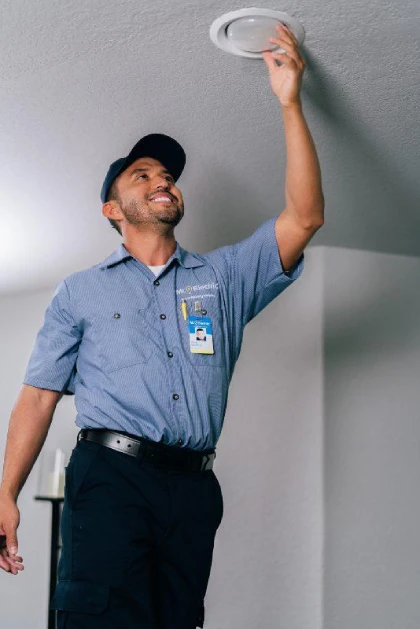 Mr. Electric electrician replacing a light bulb