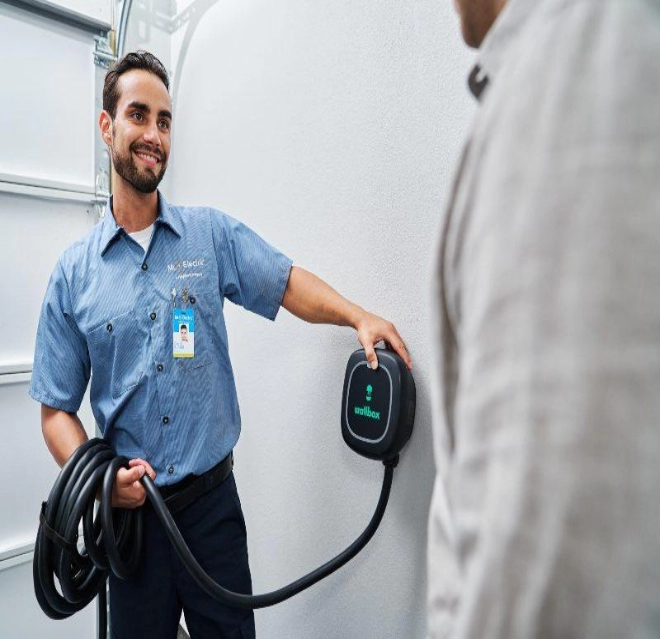 Mr. Electric electrician showing a customer a home EV charger during an installation appointment.