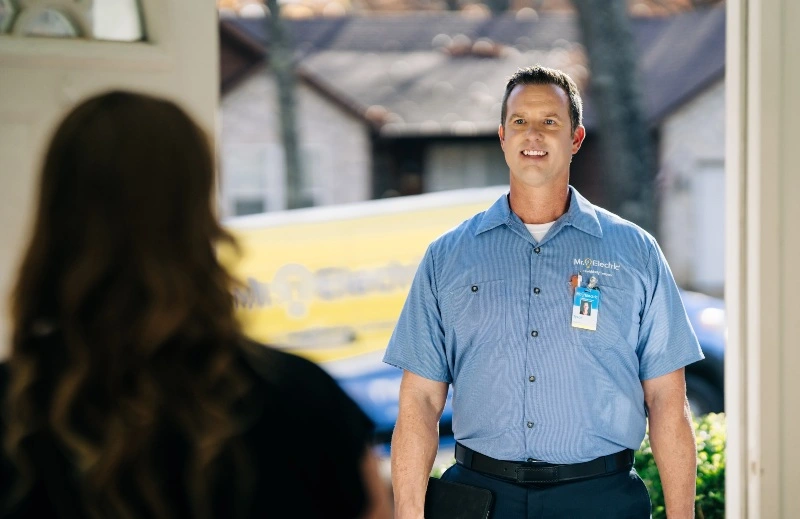 Mr. Electric electrician greets customer at her door before doing electrical wiring upgrades.