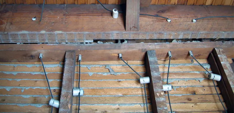 white ceramic knobs attached to joists and white ceramic tubes through joists, with wires running through knobs and tubes